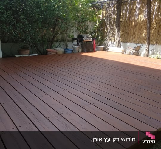 דק עץ בגינה עם עצים וצמחים מסביב